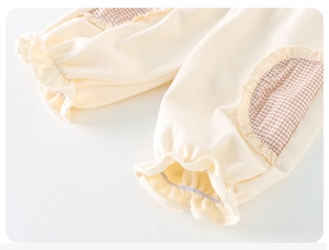 Détail du sweat-shirt pour bébé fille avec bordure en dentelle et poche à carreaux bruns