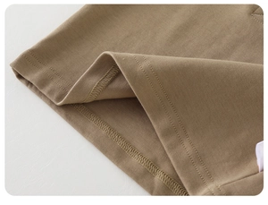 Macro detail of khaki brown cotton knit hem showing professional double-needle stitching
