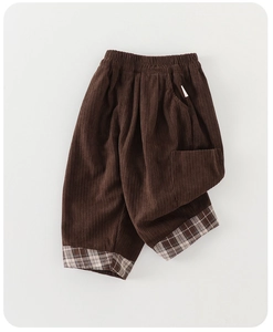 Detail of dark brown corduroy pants featuring a distinct ribbed texture and plaid cuffs
