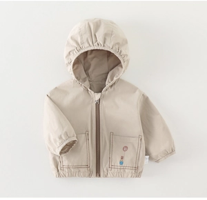 Detail einer hellbeigen Kapuzenjacke mit Reißverschluss und Cartoon-Bär-Print