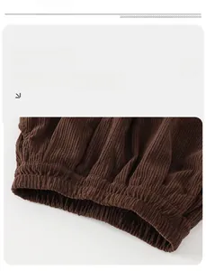 Macro detail of dark brown corduroy fabric showing the elastic cuff and vertical texture