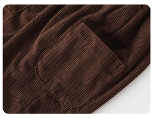 Detail view of dark brown corduroy fabric texture and pocket stitching on kids' pants