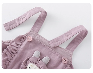 Detail of baby girl purple overall dress featuring ruffle trim and cute bunny patch