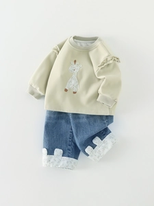 Baby girl fall outfit featuring green giraffe sweatshirt and cuffed denim pants