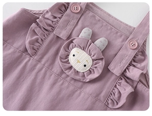 Close-up of baby romper with ruffled edges, pink buttons and a cute 3D bunny patch