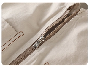Detail eines hochwertigen Silbermetall-Reißverschlusses und Nähte an einer khakifarbenen Jacke