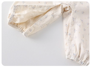 Detailed macro view of snap buttons and elastic cuffs on floral cotton baby romper