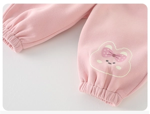 Dettaglio dei pantaloni in maglia rosa per neonata con polsini elastici e decoro