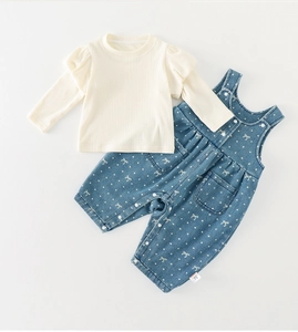 Detail of baby girl outfit with ruffles and polka dot overalls on a white background