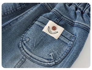 Close-up of boys denim jeans featuring elastic waistband and smiley face patch detail