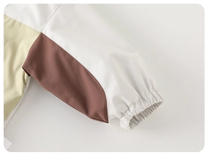 Detalle de la manga de la chaqueta cortavientos bicolor con puños elásticos en marrón
