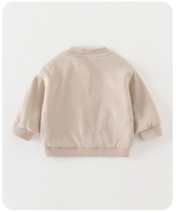 Close-up of beige waffle knit texture on children cardigan with ribbed cuffs and hem