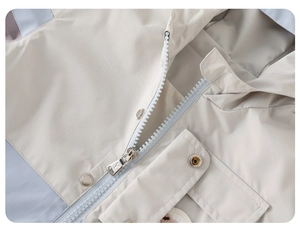 Detail of kids hooded windbreaker featuring metal zippers, press buttons, and flap pockets