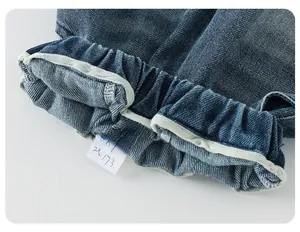Detail of blue denim fabric showing elastic cuff with gray trim and double stitching