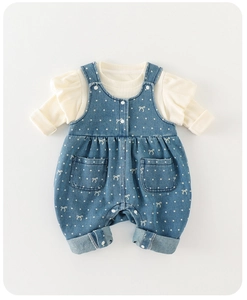Detail view of cute baby girl outfit set with white ribbed top and polka dot denim overalls