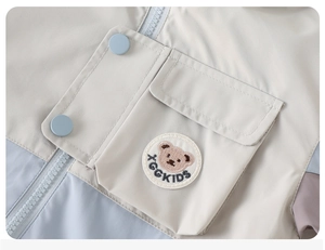 Detail of color-block kids jacket featuring a bear embroidery patch and cargo pocket