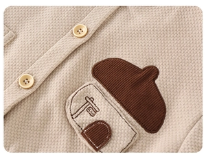 Close-up of beige waffle knit fabric with yellow buttons and house-shaped embroidery