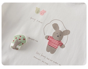 Close-up of cotton knit fabric with a cute jumping rabbit print and textile apple tree detail