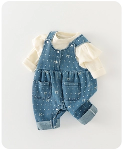 Detail of baby girl two-piece outfit with white ruffled top and polka dot bib trousers