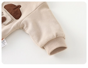Detailed macro view of beige waffle knit fabric and cute acorn embroidery on kids jacket