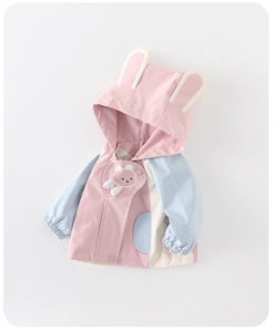 Detalle de chaqueta infantil con orejas de conejo y parche de oso en rosa y azul