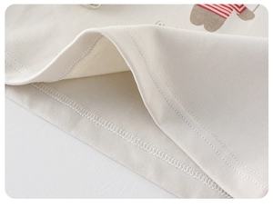 Close-up of double-needle stitching and cartoon print on off-white cotton kids' shirt