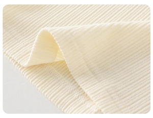 Macro shot of off-white ribbed knit fabric showing fine stitching on kids clothing
