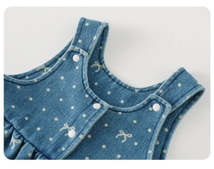 Detail of baby girl denim overalls featuring white polka dots and a cute bow print