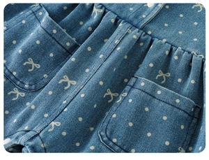 Close-up of blue denim kids clothing with white polka dots, bow prints and side pockets