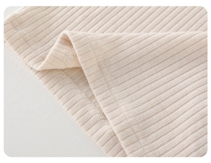 Nahaufnahme der gerippten Strickstruktur und der sauberen Nähte des beigefarbenen Babyshirts