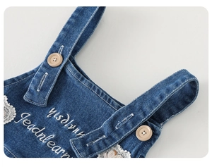 Detailansicht der Baby-Jeanslatzhose mit weißer Blumenspitze und Stickerei-Verzierung