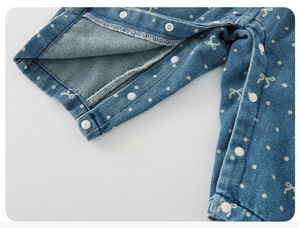Detailed macro view of baby denim overalls with white polka dots and resin snap buttons