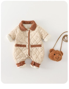 Detailed macro view of beige quilted cotton baby romper with cute bear prints and corduroy trim