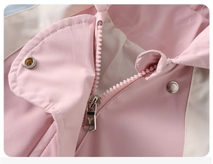 Detalle de chaqueta rosa y beige que muestra cremallera metálica y cuello alto corta