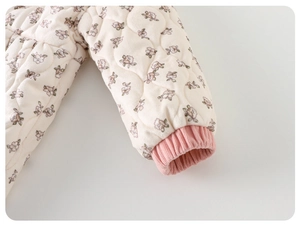 Détail d'une barboteuse matelassée fleurie pour bébé montrant les poignets en tricot