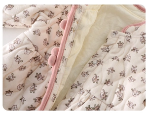 Détail du body matelassé pour bébé avec imprimé fleuri et pompons roses au col