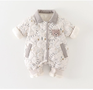 Detail of baby quilted romper featuring forest prints and soft 3D bear applique patch