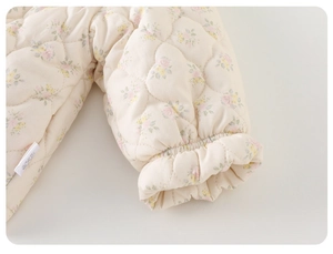 Detail of floral quilted baby suit showing elastic cuffs and soft fabric texture