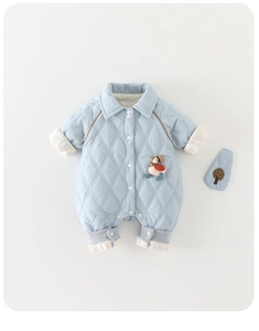 Detailed view of light blue quilted baby jumpsuit with cute 3D duck and embroidered bib