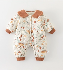 Detalle de pelele acolchado para bebé con estampado floral y cuello de pana marrón