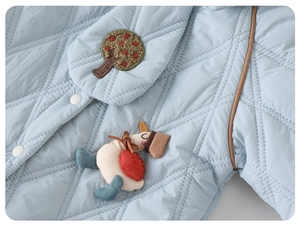 Close-up of baby quilted jumpsuit featuring light blue fabric with diamond stitching and buttons