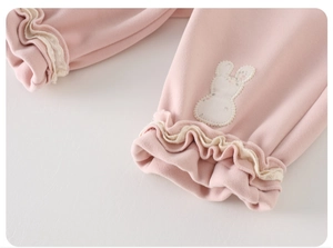 Detail of pink baby trousers featuring ruffle cuffs and a white bunny patch embroidery