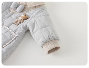 Détail d'une grenouillère matelassée pour bébé avec texture bleue et petit ours en peluche