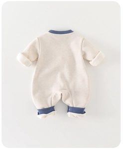 Dettaglio tutina neonato con polsini a costine blu e morbido cotone color crema