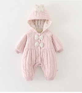 Detailed close-up of pink quilted baby romper with floral lining and bow accents