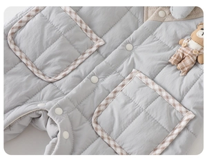 Détail de la grenouillère matelassée pour bébé avec motif losanges et petit ours mignon