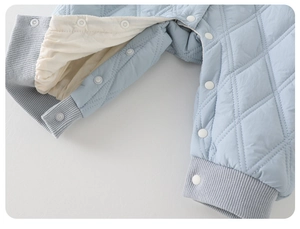 Detail of light blue quilted baby romper with white snap buttons and ribbed cuffs