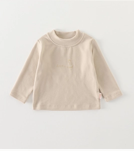 Détail du haut thermique beige montrant le col montant et la broderie minimaliste