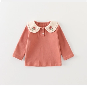 Close-up of baby romper with floral embroidery on white Peter Pan collar and soft fabric