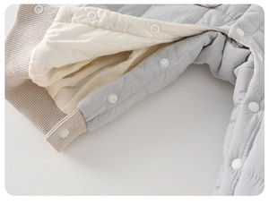 Détail de la barboteuse matelassée bébé montrant la doublure, boutons pression et bords